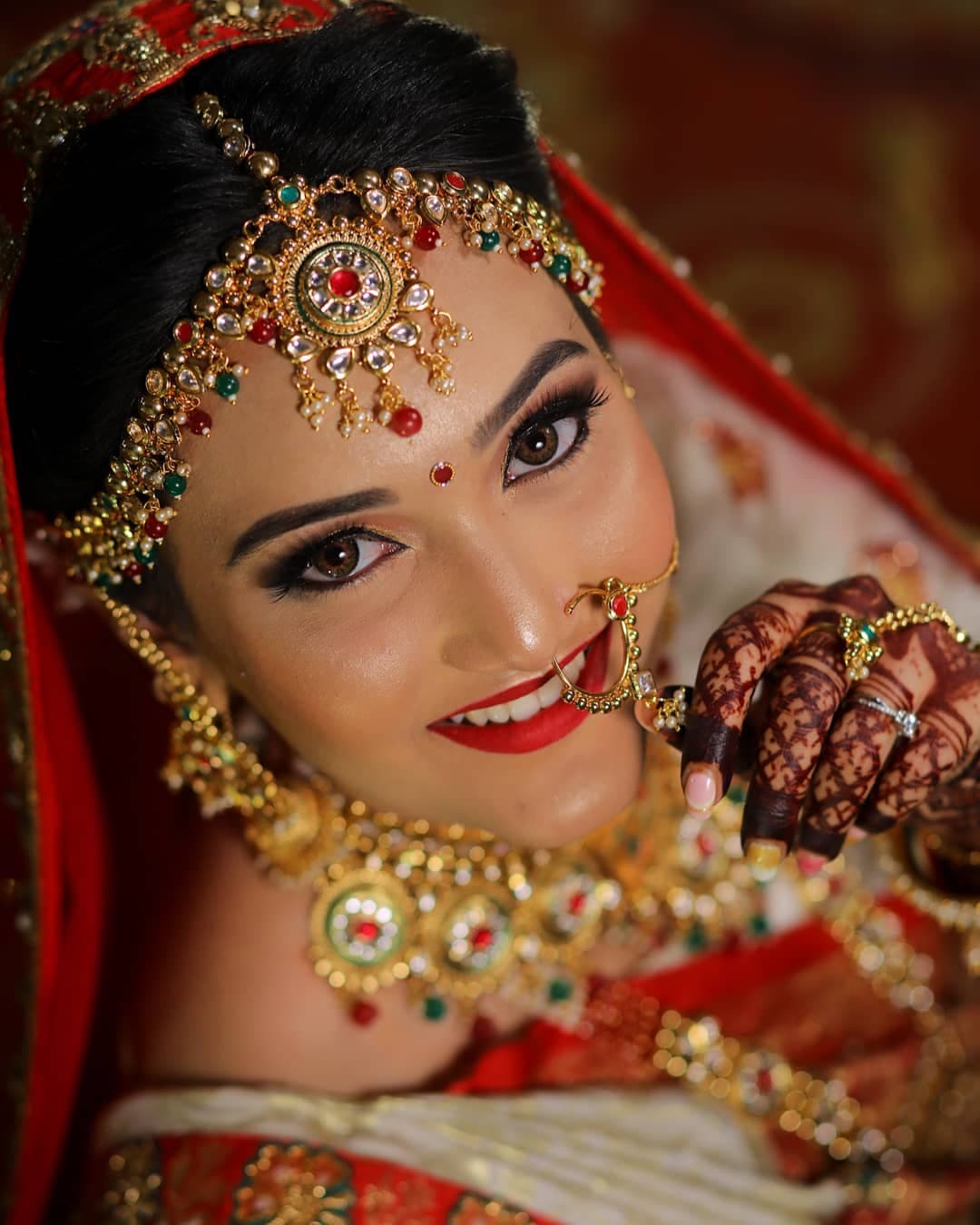 Bride in red with traditional gold jewellery and a luminous makeup look